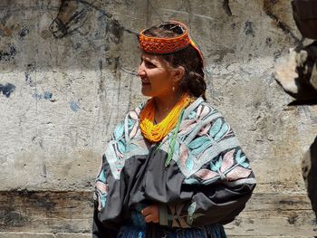 Woman in traditional clothes standing against wall