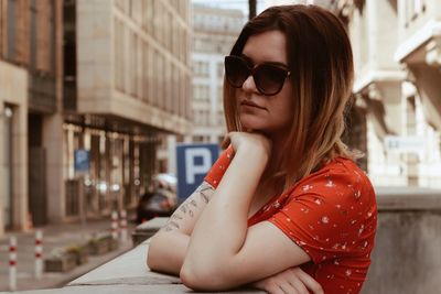 Young woman wearing sunglasses against buildings in city