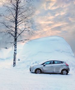 Car on snow covered landscape against sky