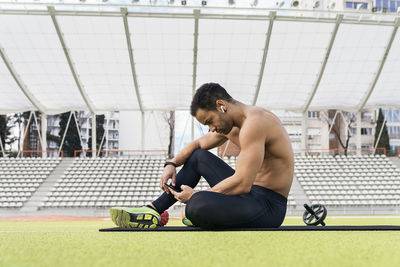 Side view of young man sitting on floor