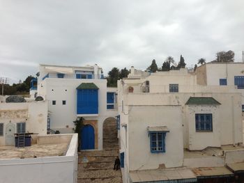 Buildings in town against cloudy sky