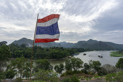Scenic view of flag by mountains against sky