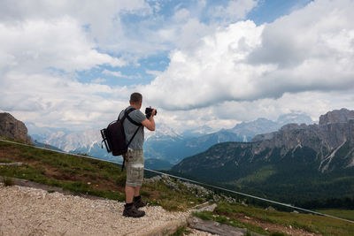 Side view of man standing on mountain against cloudy sky