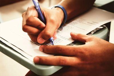 Cropped hands writing on paper at table