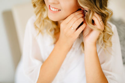 Midsection of woman wearing earring at home