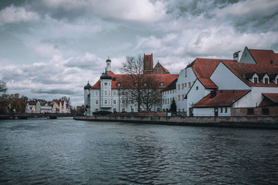 Buildings by river against sky