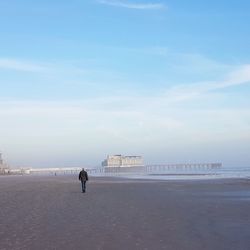 Man walking on beach against sky