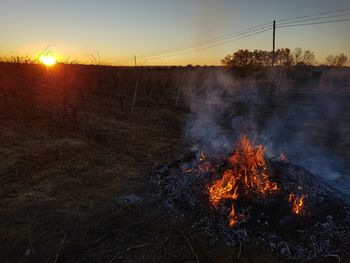 Bonfire on field against sky at sunset