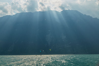 People on mountain by sea against sky