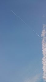 Low angle view of vapor trails against blue sky