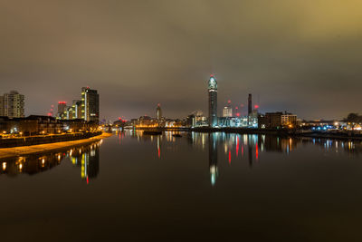 Reflection of illuminated buildings in river against sky