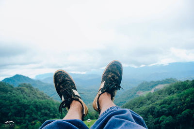 Low section of person on mountain against sky