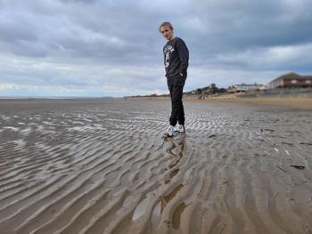 Full length of man standing at beach against sky