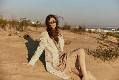 Portrait of young woman standing at sandy beach