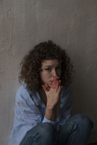 Portrait of teenage girl eating against wall