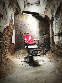 Abandoned chair against wall in old building