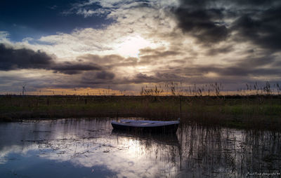 Boat in water against sky during sunset