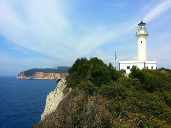 Lighthouse on hill against cloudy sky