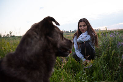 Woman with dog on field against sky