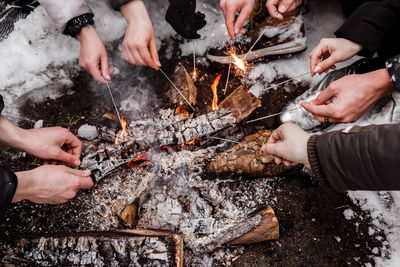 Cropped hands of people burning sparklers outdoors