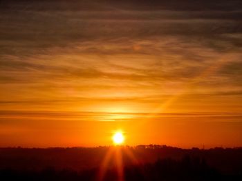 Scenic view of silhouette landscape against orange sky