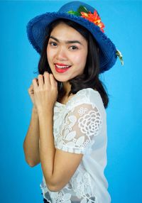 Portrait of smiling young woman standing against blue wall