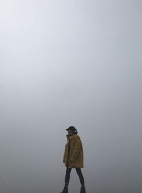 Rear view of man standing on rock against sky