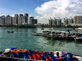 Boats in sea by cityscape against sky