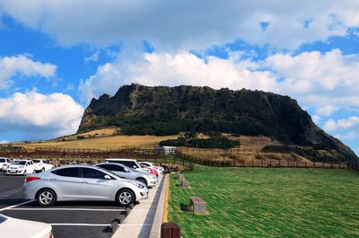 Cars on road by mountain against sky