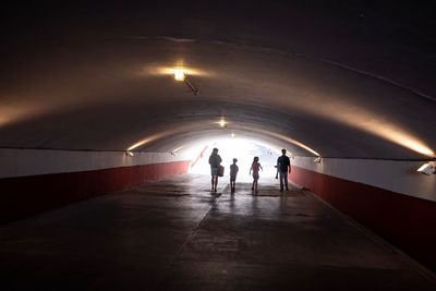 Rear view of people walking in tunnel