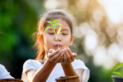 Close-up of girl holding plant in hand outdoors