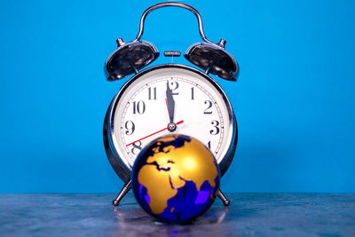 Close-up of clock on table against blue wall