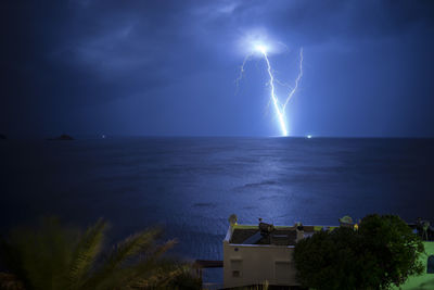Firework display over sea against sky at night