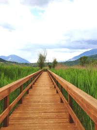 Surface level of wooden footbridge against sky