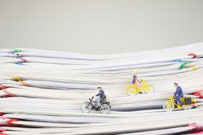 Figurines with toy bicycles on stacked papers