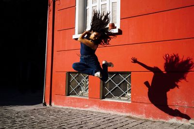 Side view of girl with arms raised against wall