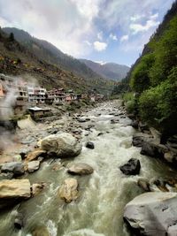 Stream flowing through rocks against sky