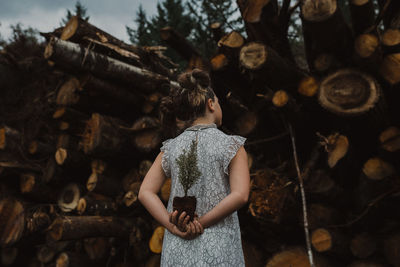 Girl stand among forest fire fallen tree wall 