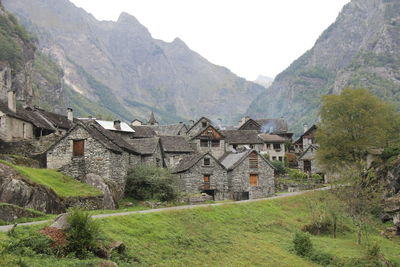 Houses on field by mountain against sky