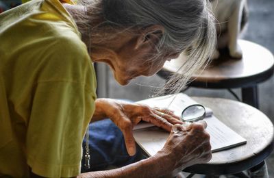 Close-up of senior woman reading book while sitting at home