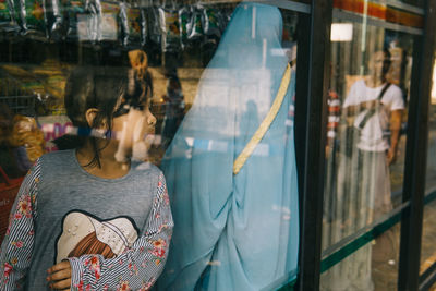 Girl looking through window in store