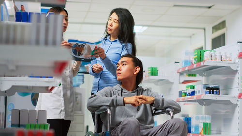 Side view of young woman using mobile phone while standing in laboratory