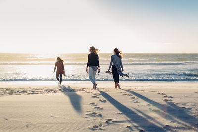 People walking on beach against clear sky