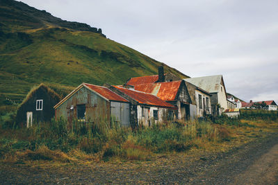 Houses on landscape against cloudy sky