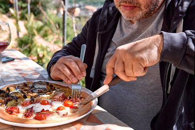 Man cutting pizza in the plate on tile table in the garden. homemade italian pizza. 