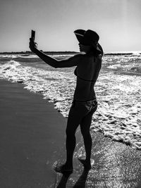 Full length of woman standing at beach against sky