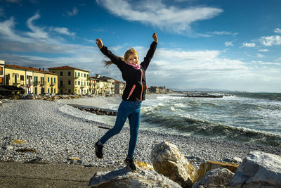 Full length of boy standing at sea shore against sky