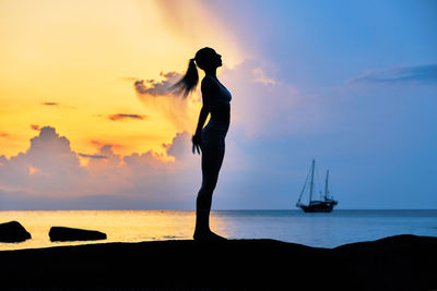 Woman standing on beach against sky during sunset