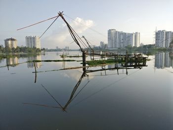 Modern buildings by river against sky in city