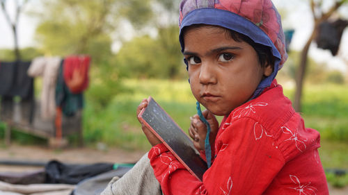 Cute little indian girl writing 123 on black school slate board, isolated over garden background.